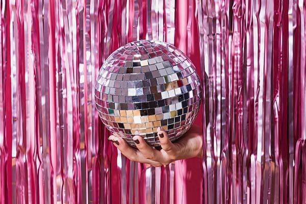 glob disco tinut in mana in fata unui fundal cu paiete roz pentru cabina foto la un eveniment